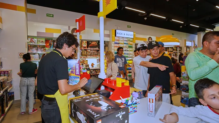 Niños y adultos comprando sets de construcción en la tienda LEGO durante el Buen Fin