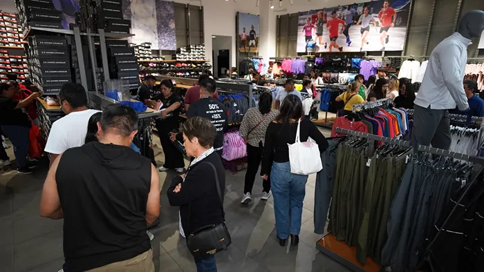 Clientes revisando outfits deportivos en la tienda Under Armour de la plaza