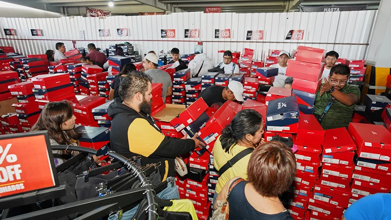 Personas comprando calzado con descuento en la Venta de Estacionamiento Outlet